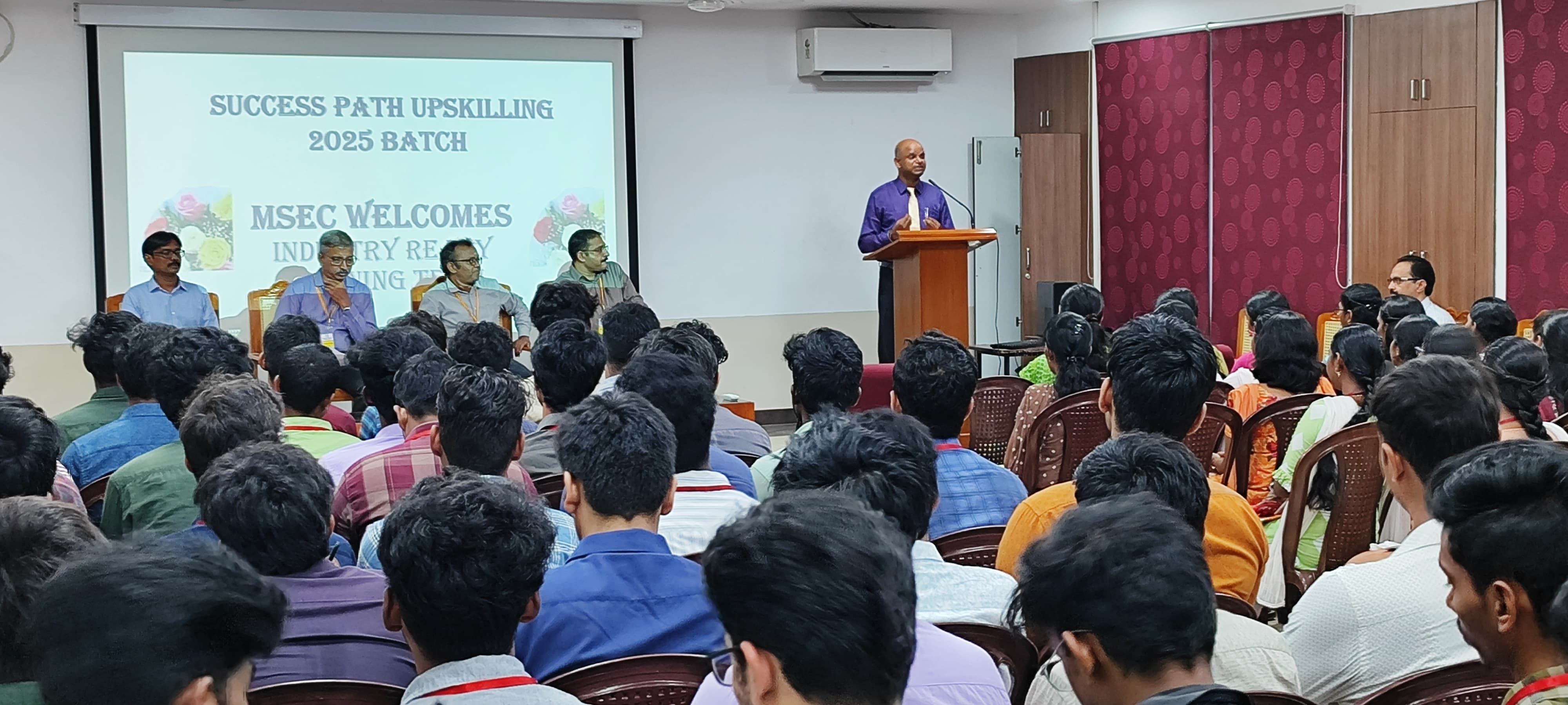A full auditorium of students facing a speaker at a lectern during an upskilling programme