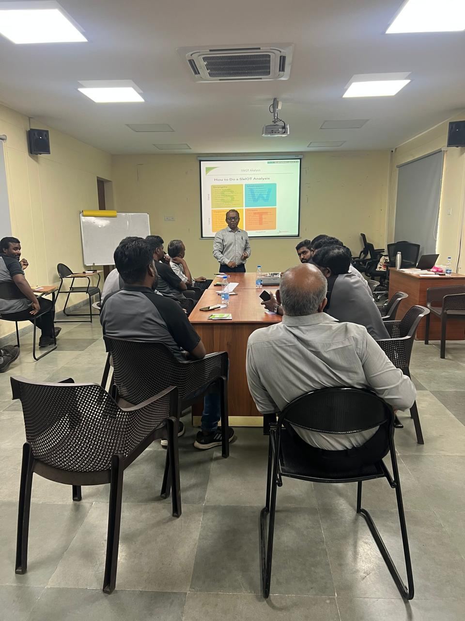 Participants seated around a table facing a presentation screen in a workshop room